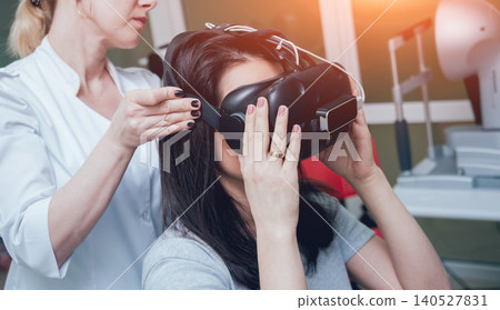 Ophthalmology doctor checks the girl's vision with the help of virtual reality goggles. 140527831