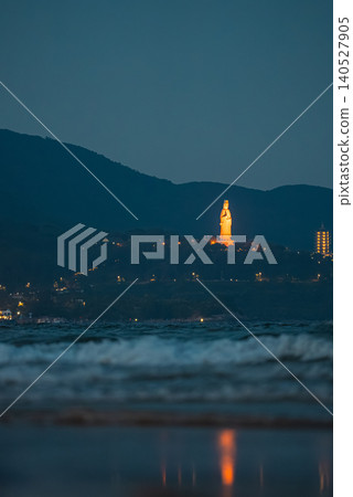 illuminated Lady Buddha statue and Linh Ung Pagoda above coastline with sea waves and mountains in Da Nang, Coastal landscape with ocean waves and Son Tra Peninsula at night, Danang Vietnam illuminated Lady Buddha statue and Linh Ung Pagoda above coastline with sea waves and mountains in Da Nang, Coastal landscape with ocean waves and Son Tra Peninsula at night, Danang Vietnam 140527905