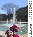 A scene with pink flowers in the foreground and a fountain in the background. 140528059