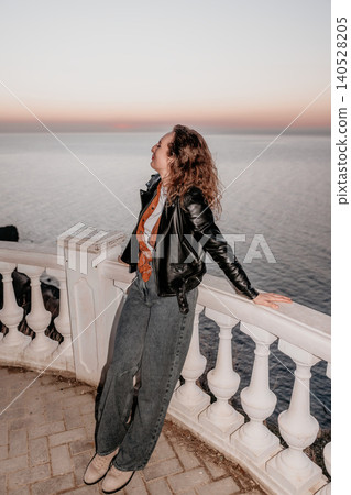 Woman sunset coast relaxing on a white marble balcony while watching the golden hour light over the calm ocean horizon Woman sunset coast relaxing on a white marble balcony while watching the golden hour light over the calm ocean horizon 140528205