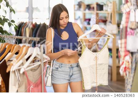 Young woman choosing top in clothing store 140528363