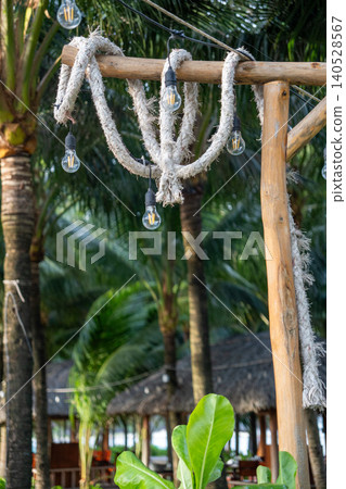 Rustic tropical resort decor with hanging vintage light bulbs and rope details surrounded by palm trees in Vietnam. Rustic tropical resort decor with hanging vintage light bulbs and rope details surrounded by palm trees in Vietnam. 140528567