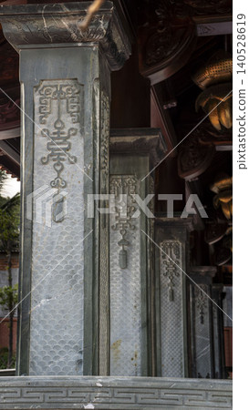Close-up of intricately carved grey stone columns with traditional Vietnamese decorative symbols at the Ho Chi Minh memorial temple in Vietnam. Detailed craftsmanship. 140528619