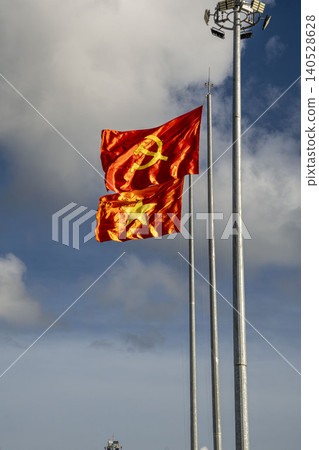 Vietnamese national flag and Communist Party flag waving dramatically in the wind on tall flagpoles against a stormy cloudy sky in Vietnam. Patriotic symbolism. Vietnamese national flag and Communist Party flag waving dramatically in the wind on tall flagpoles against a stormy cloudy sky in Vietnam. Patriotic symbolism. 140528628