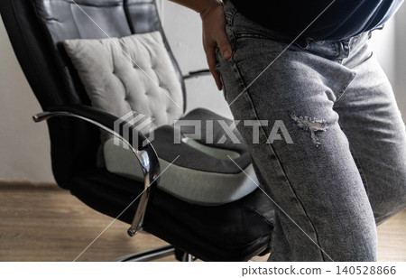 Man uses orthopedic cushion for lower back pain relief. Cushion addresses spinal discomfort, herniated disc, osteochondrosis, protrusion issues. Pain from trigger points in muscles Man uses orthopedic cushion for lower back pain relief. Cushion addresses spinal discomfort, herniated disc, osteochondrosis, protrusion issues. Pain from trigger points in muscles 140528866
