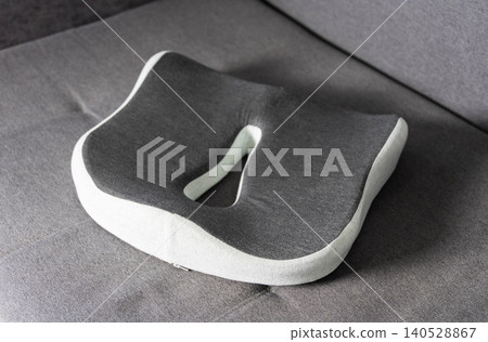 Modern orthopedic memory foam seat cushion, ergonomic design for coccyx and posture support, grey and white color, product photography Modern orthopedic memory foam seat cushion, ergonomic design for coccyx and posture support, grey and white color, product photography 140528867