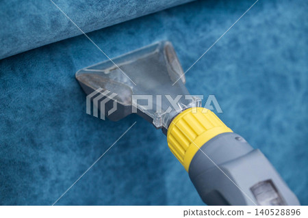 Cleaning a blue fabric surface with a specialized tool for upholstery maintenance and deep cleaning Cleaning a blue fabric surface with a specialized tool for upholstery maintenance and deep cleaning 140528896