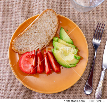 Fresh sliced avocado and tomato arranged on plate 140528910