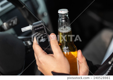 Man In Car Holding Beer Bottle And Breathalyzer. Concept Of Driving Under The Influence. 140528981