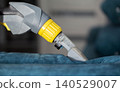 Detailed cleaning of a blue upholstery fabric using a specialized cleaning tool in an indoor setting 140529007