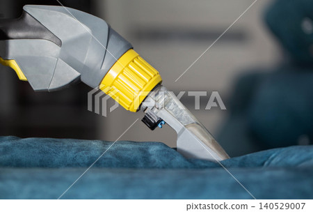 Detailed cleaning of a blue upholstery fabric using a specialized cleaning tool in an indoor setting Detailed cleaning of a blue upholstery fabric using a specialized cleaning tool in an indoor setting 140529007
