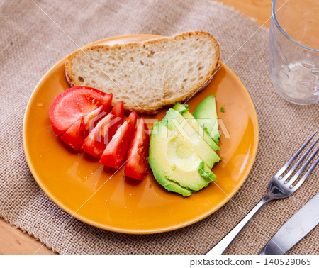 Sliced avocado and tomato on a plate top view Sliced avocado and tomato on a plate top view 140529065