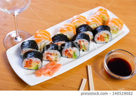 Assorted different types of maki, uramaki, with salmon, served with bowl of soy sauce on plate in restaurant Assorted different types of maki, uramaki, with salmon, served with bowl of soy sauce on plate in restaurant 140529082