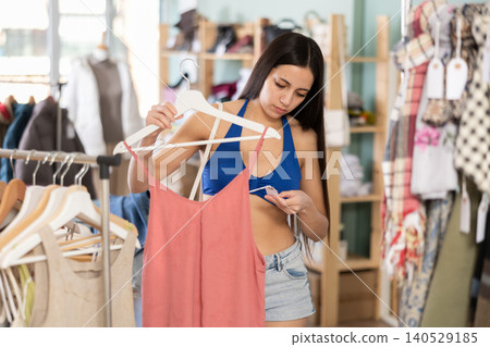 Young woman choosing jumpsuit in clothing store Young woman choosing jumpsuit in clothing store 140529185