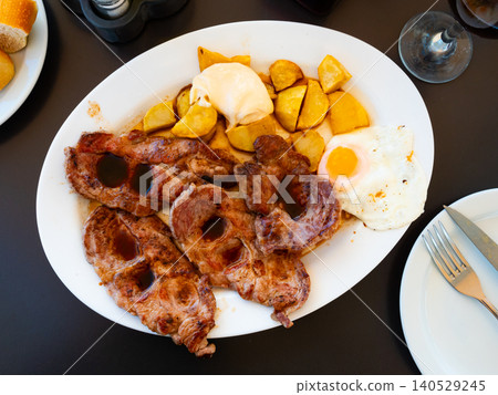 Fried pork with potatoes and fried eggs on plate 140529245