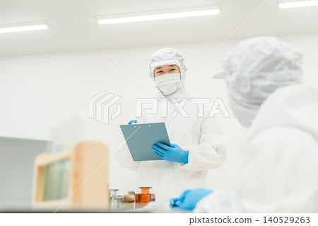 Staff wearing clean suits developing drugs at a pharmaceutical factory or pharmaceutical company Staff wearing clean suits developing drugs at a pharmaceutical factory or pharmaceutical company 140529263