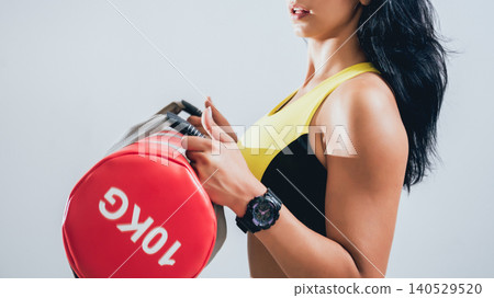 Athletic young woman training with sandbags at gray background. Crossfit center Athletic young woman training with sandbags at gray background. Crossfit center 140529520