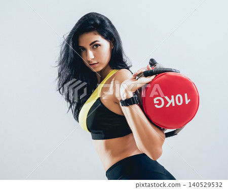 Athletic young woman training with sandbags at gray background. Crossfit center Athletic young woman training with sandbags at gray background. Crossfit center 140529532