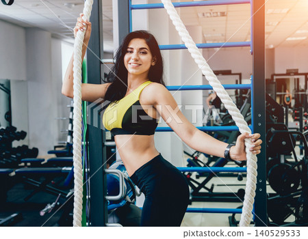 Beautiful athletic young woman making exercise at the gym. Young woman with muscular body. Beautiful athletic young woman making exercise at the gym. Young woman with muscular body. 140529533