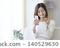A woman enjoys online shopping at home using her smartphone and credit card. 140529630