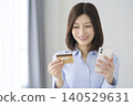 A woman shopping online using her smartphone; cashless payment; e-commerce. 140529631