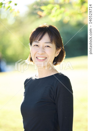 秋日的公園裡,一位面帶微笑的四十多歲女舞者。 秋日的公園裡,一位面帶微笑的四十多歲女舞者。 140529714