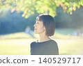 A female dancer in her 40s turns to the side in an autumn park. 140529717