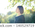 A female dancer in her 40s turns to the side in an autumn park. 140529719
