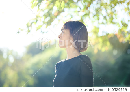 A female dancer in her 40s turns to the side in an autumn park. A female dancer in her 40s turns to the side in an autumn park. 140529719