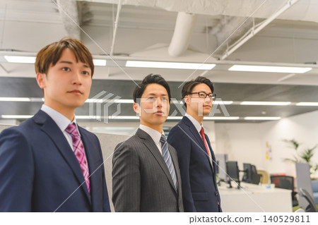 Two businessmen standing side by side in an office. Two businessmen standing side by side in an office. 140529811