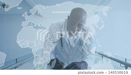 Leaning male physician wearing lab coat writing paper in clinic hall, with stethoscope and map Leaning male physician wearing lab coat writing paper in clinic hall, with stethoscope and map 140530019