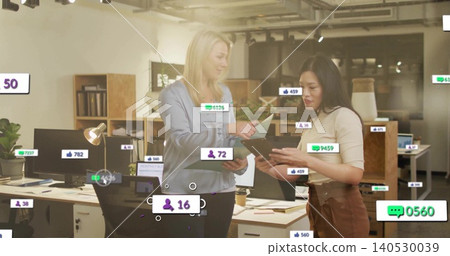Discussing two coworkers in blouses reviewing tablet and papers at office desk with social overlays Discussing two coworkers in blouses reviewing tablet and papers at office desk with social overlays 140530039