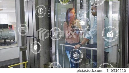 Colleagues in pink blouse, blue shirt discussing in glass elevator, showing tablet with UI icons Colleagues in pink blouse, blue shirt discussing in glass elevator, showing tablet with UI icons 140530210