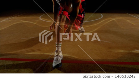 Reaching male basketball player stretching knees on hardwood court lines, red shorts, white shoes Reaching male basketball player stretching knees on hardwood court lines, red shorts, white shoes 140530242