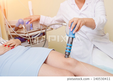 Shock wave therapy. The magnetic field, rehabilitation. Physiotherapist doctor performs surgery on a patient's knee Shock wave therapy. The magnetic field, rehabilitation. Physiotherapist doctor performs surgery on a patient's knee 140530411