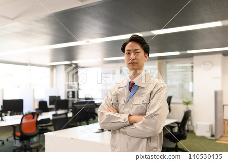一名建築公司男子雙手交叉放在胸前站在辦公室。 一名建築公司男子雙手交叉放在胸前站在辦公室。 140530435