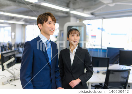 Men and women in suits facing forward in an office. Men and women in suits facing forward in an office. 140530442