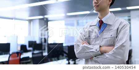 A male worker with his arms crossed in the office. 140530454