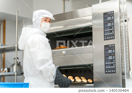 A man working in a bread factory or food factory wearing a dustproof suit or clean suit A man working in a bread factory or food factory wearing a dustproof suit or clean suit 140530464