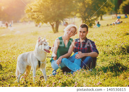 Dog with owners spend a day at the park. Young couple and husky running, playing and having fun. Dog with owners spend a day at the park. Young couple and husky running, playing and having fun. 140530815