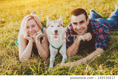 Dog with owners spend a day at the park. Young couple and husky running, playing and having fun. 140530817