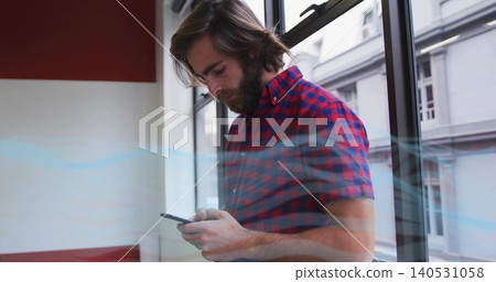 Holding smartphone, bearded man in red checked shirt standing by window, viewing screen reflections Holding smartphone, bearded man in red checked shirt standing by window, viewing screen reflections 140531058