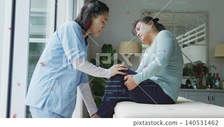 Assessing nurse in scrubs supporting seated patient's knee at home clinic exam bench window Assessing nurse in scrubs supporting seated patient's knee at home clinic exam bench window 140531462