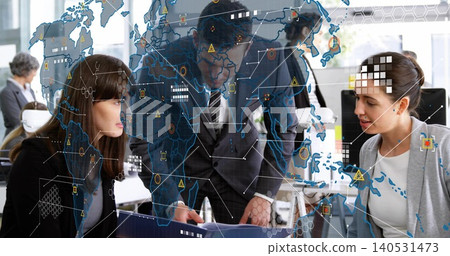 Pointing, three coworkers in suits leaning over desk at open office, with binder and map overlay Pointing, three coworkers in suits leaning over desk at open office, with binder and map overlay 140531473