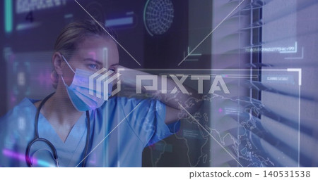 Standing clinician wearing blue scrubs and surgical mask in clinic by blinds, stethoscope holograms Standing clinician wearing blue scrubs and surgical mask in clinic by blinds, stethoscope holograms 140531538