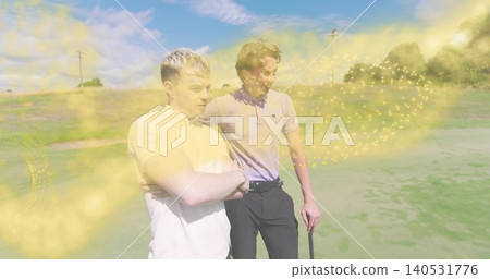 Standing two men wearing polos, putting arm around and holding golf club at green, golden sparkles Standing two men wearing polos, putting arm around and holding golf club at green, golden sparkles 140531776