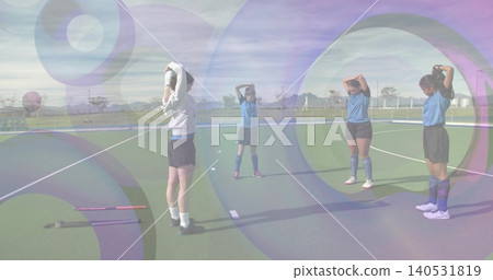 Stretching four players in blue shirts raising hands on turf, with two field hockey sticks Stretching four players in blue shirts raising hands on turf, with two field hockey sticks 140531819