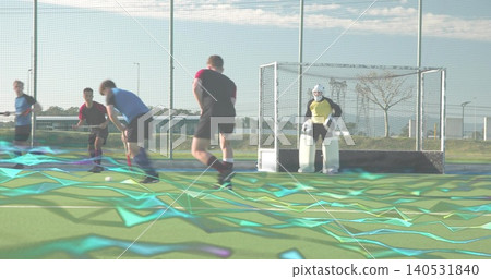 Advancing hockey players running toward ball on turf with teal overlay, keeper wearing yellow kit Advancing hockey players running toward ball on turf with teal overlay, keeper wearing yellow kit 140531840
