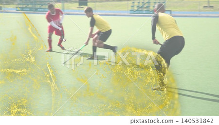 Controlling central player in yellow bib bending on turf with hockey stick, red kit, yellow overlay 140531842