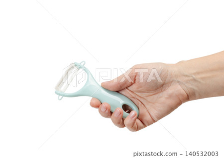 Vegetable peeler in the woman's hand on the white background. Vegetable peeler in the woman's hand on the white background. 140532003